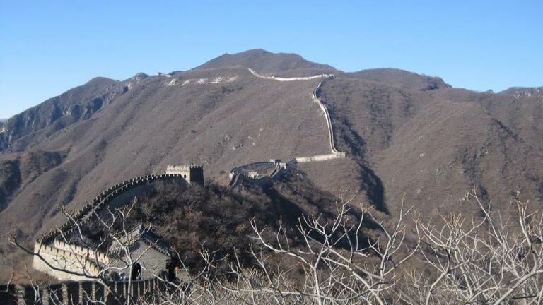 Zu sehen ist die chinesische Mauer von Weitem in ihrem Verlauf einen Berg hinauf